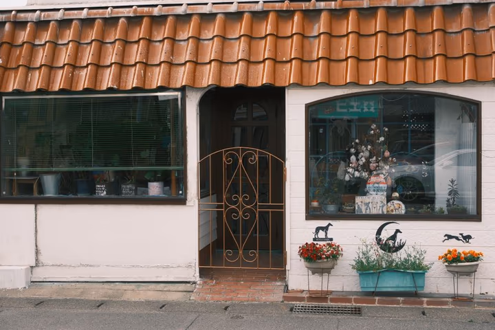 Devanture d'une boutique japonaise pittoresque décorée d'un portail ouvragé et de fleurs colorées.